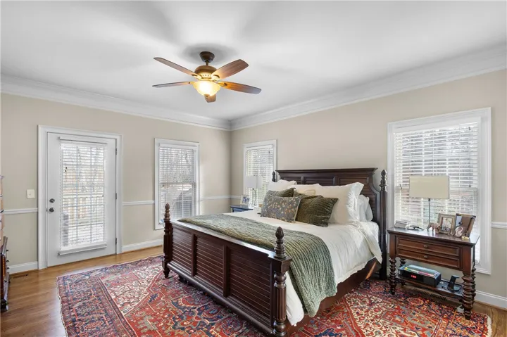 This tranquil bedroom offers comfort and a private outdoor connection, featuring rich hardwood floors.