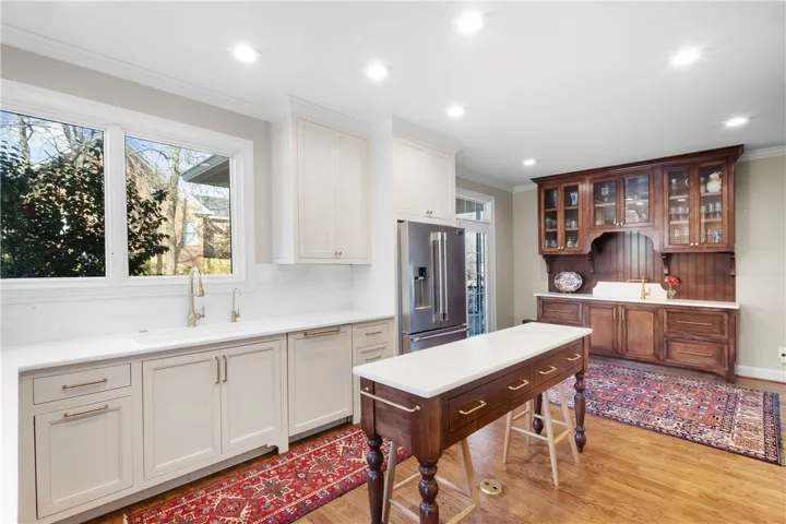 This kitchen features a bright ambiance, sleek appliances, and elegant wood flooring.