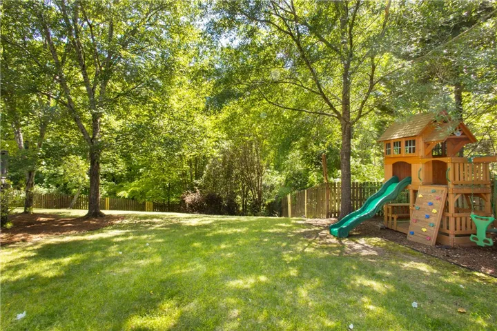 This spacious yard offers a vibrant green lawn and mature trees, perfect for outdoor activities.
