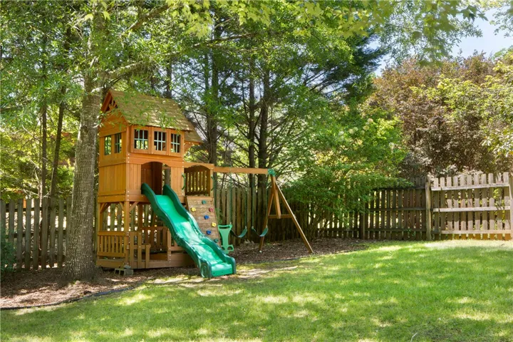 This spacious yard features a wooden play structure and swing set, perfect for outdoor fun.