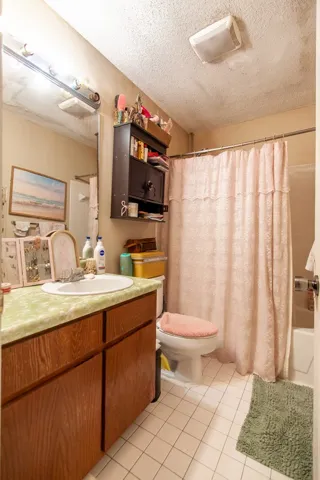 This bathroom features a functional vanity with a light green countertop and tiled flooring.