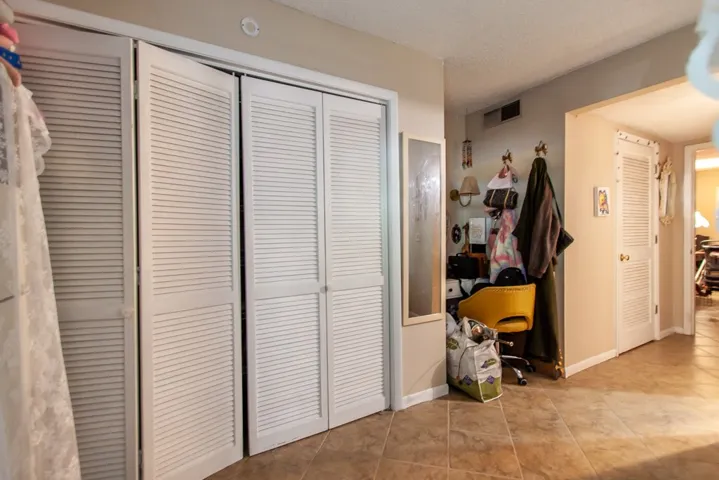 This interior hallway features functional louvered closet doors and durable tile flooring.