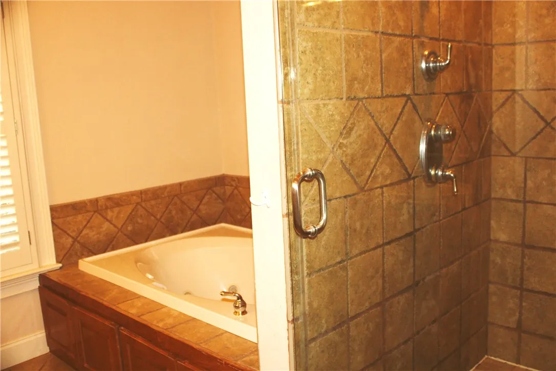 Relax and refresh in this tranquil bathroom, featuring a built-in tub and tiled shower.