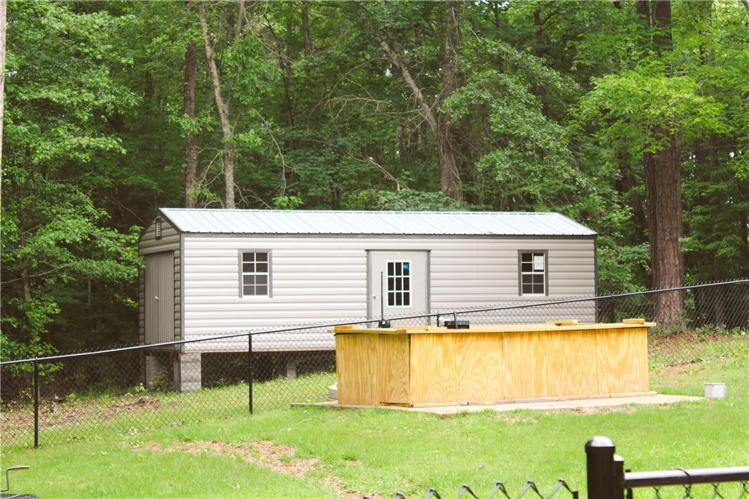 This outdoor storage shed is set against a lush, wooded backdrop, offering practical utility.