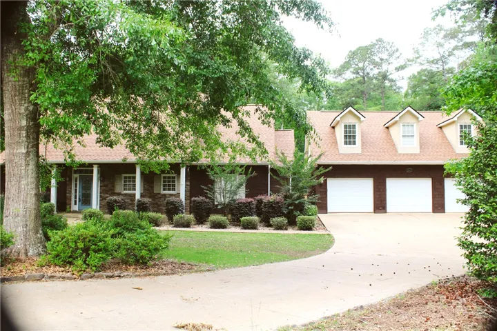 This charming residence features a well-manicured lawn, a classic shingle roof, and a convenient attached garage.