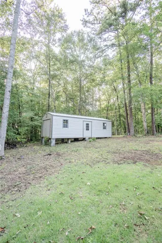 A versatile outbuilding set within a wooded lot provides ample storage or flexible utility space.