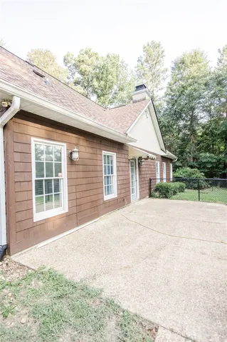 A spacious concrete patio extends from this home's wood-shingled exterior, offering a private outdoor retreat.