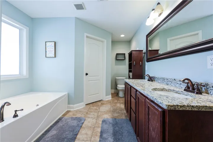This serene bathroom offers a spacious soaking tub and a functional double vanity with a walk in closet.