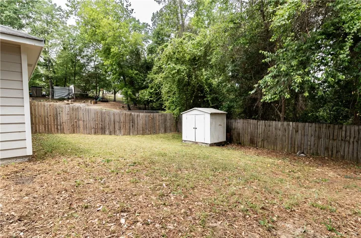 Backyard with privacy fence and storage building.