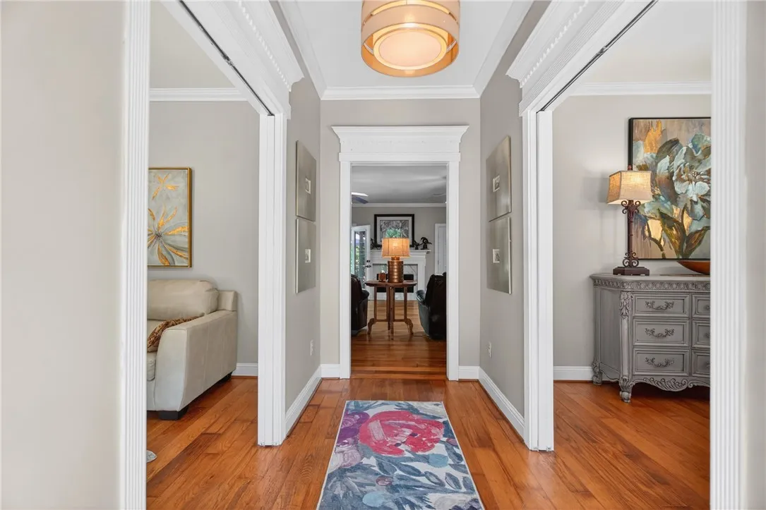 This inviting hallway features rich hardwood flooring and elegant crown molding, creating a warm welcome.