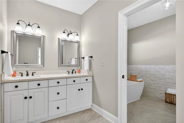 This primary bathroom features a dual vanity with ample storage and a luxurious soaking tub.