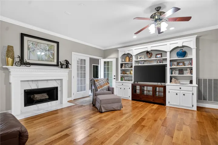 This living room features a cozy fireplace, hardwood flooring, and ample built-in shelving.