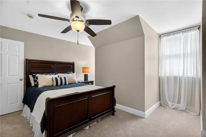 This cozy bedroom features sloped ceilings and ample natural light through a large window.