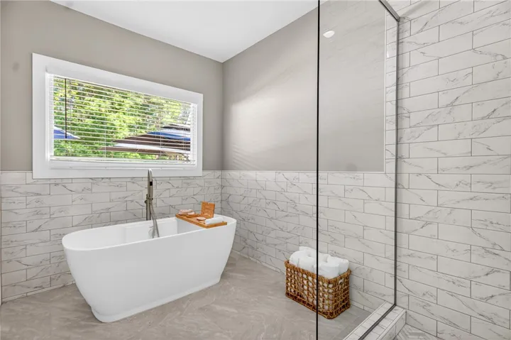 This serene bathroom offers a spacious soaking tub and a sleek, modern glass shower.