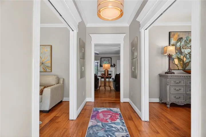 This inviting hallway features rich hardwood flooring and elegant crown molding, creating a warm welcome.