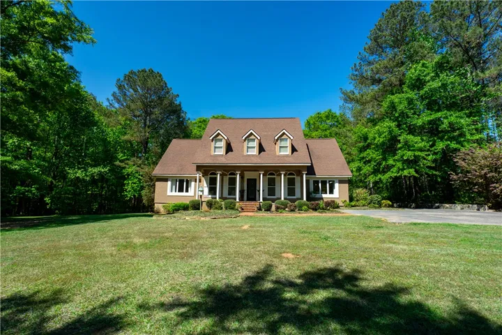 This classic dwelling offers a welcoming facade with a lush green lawn and mature trees.