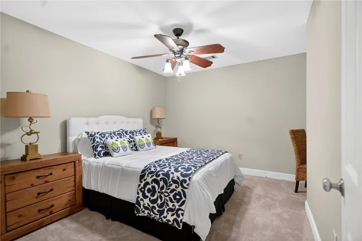 This cozy bedroom features plush carpeting and a ceiling fan, creating a comfortable and inviting atmosphere.