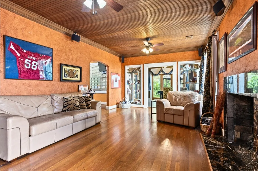 Living room with original wood floors, open to dining room and patio