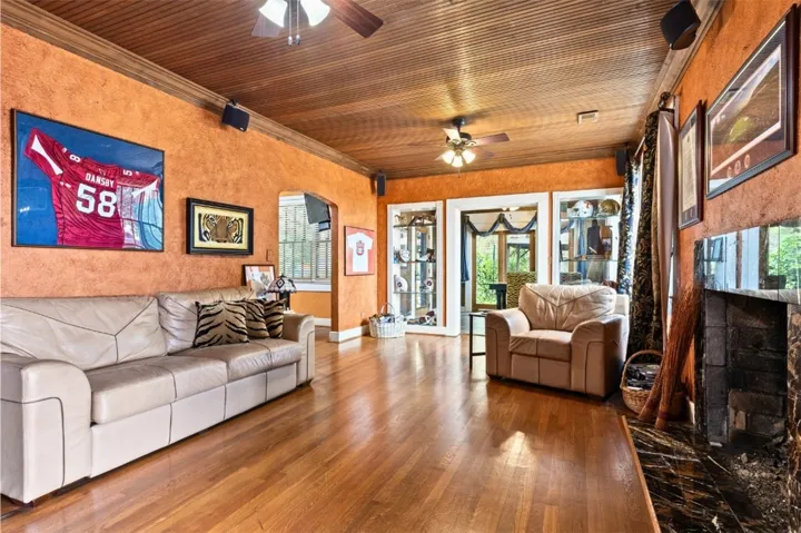 Living room with original wood floors, open to dining room and patio