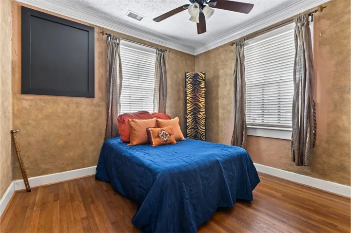This cozy bedroom features durable hardwood flooring and elegant crown molding.