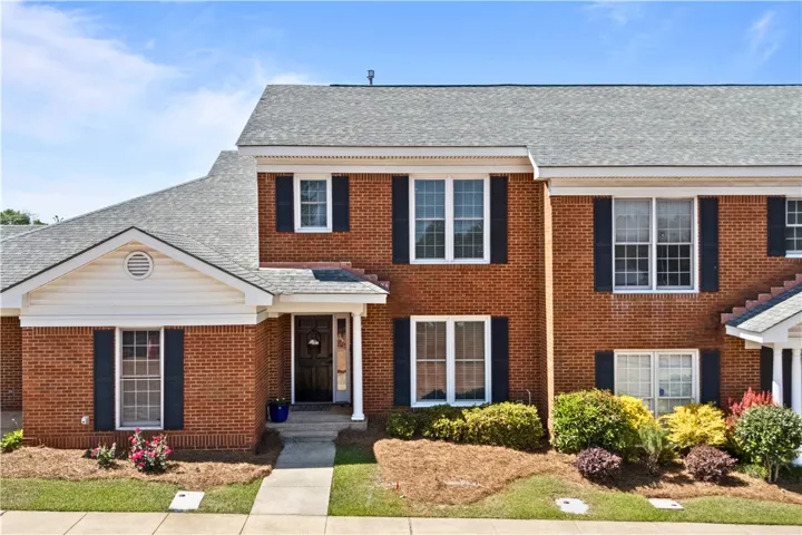 Classic brick townhome featuring a welcoming front entry and a well-maintained exterior.