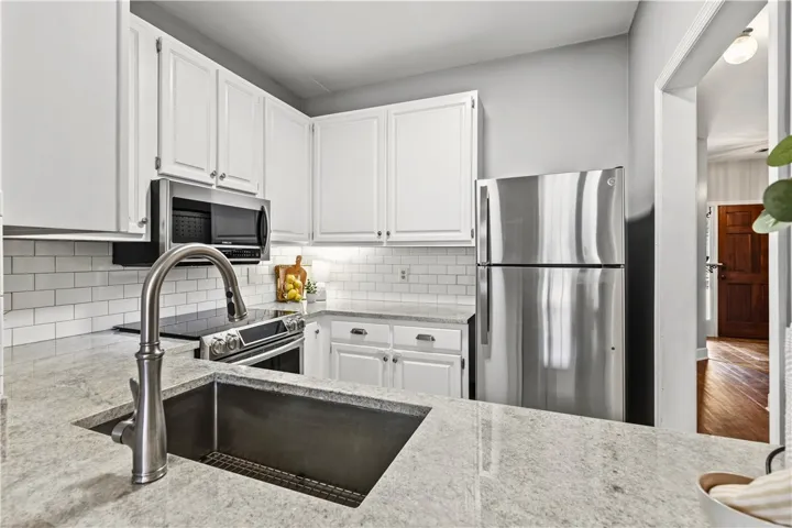 This modern kitchen features granite countertops, white cabinetry, and stainless steel appliances (negotiable).