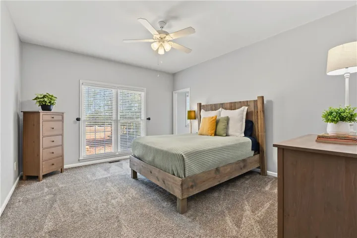 This cozy bedroom features a ceiling fan, young, plush carpet, and fantastic natural lighting.