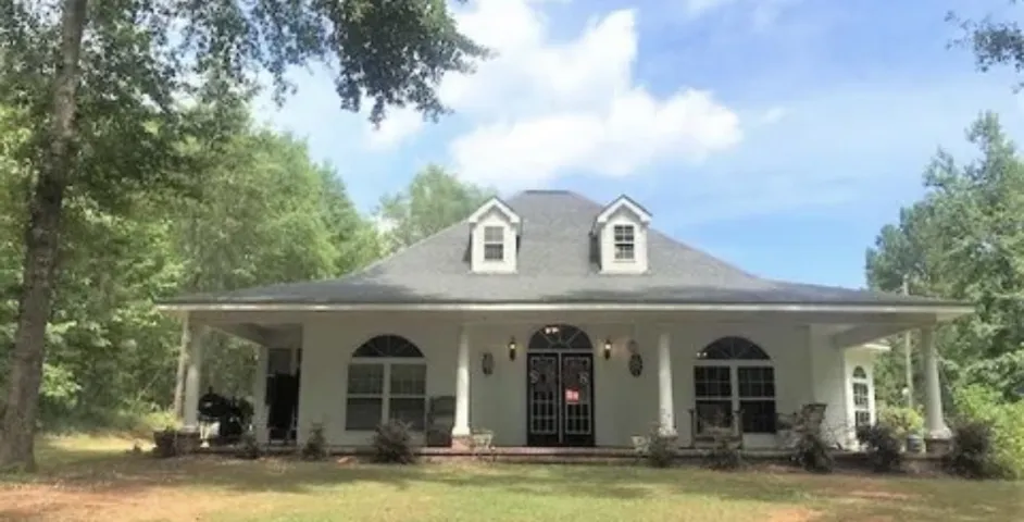 This charming home offers a wide front porch and dormer windows, nestled among mature trees.