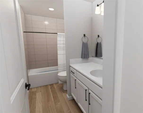 This bathroom features elegant hardwood flooring, a pristine white vanity with a single sink, and a tiled shower.