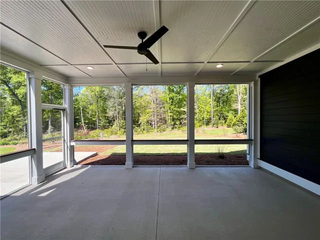 Enjoy tranquil wooded views from this inviting screened porch, perfect for peaceful moments outdoors.