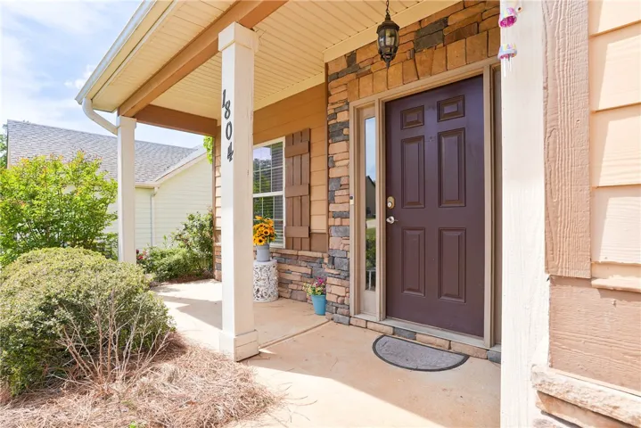 The inviting entrance features a covered porch, stone accents, and a warm brown door.