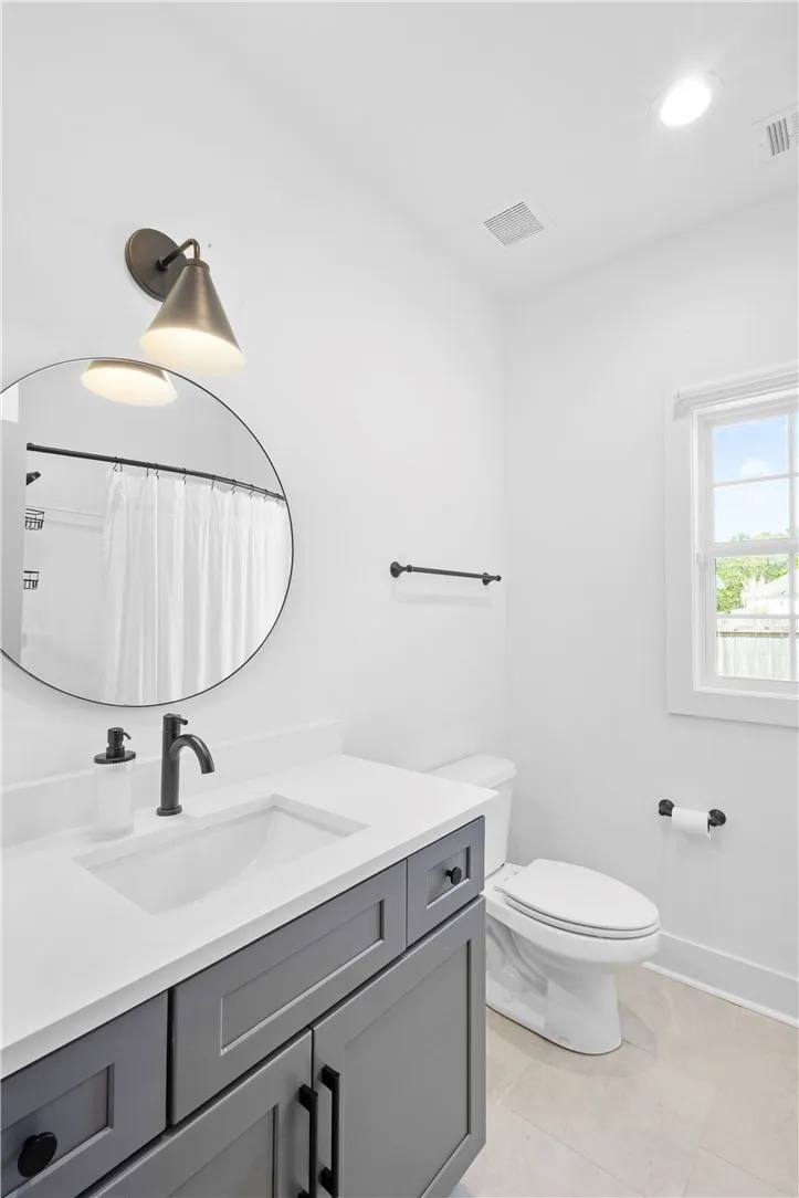 A pristine bathroom featuring a sleek vanity and modern fixtures under a wall-mounted light.