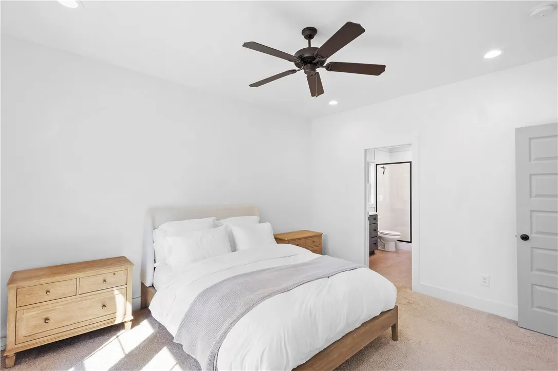 A well-lit bedroom features plush carpeting and a spacious ceiling fan for optimal comfort.