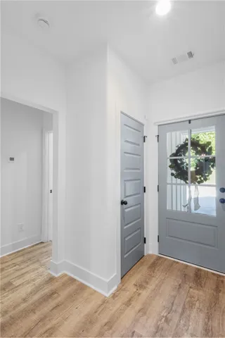 A well-lit entry hall with wood flooring and a classic paneled door welcomes all.