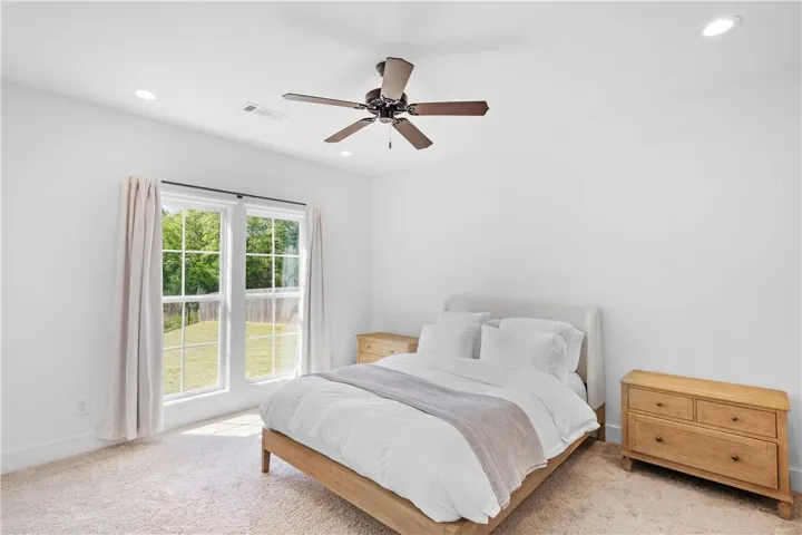 A tranquil bedroom provides comfort and expansive views of the outdoors through broad windows.