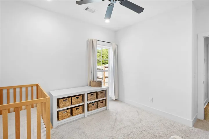 A well-lit bedroom featuring a built-in storage unit, soft carpet, and a pleasant outdoor view.