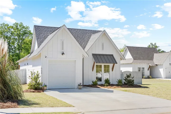 This residence features a crisp white facade with a matching garage door, complemented by a neatly paved driveway.