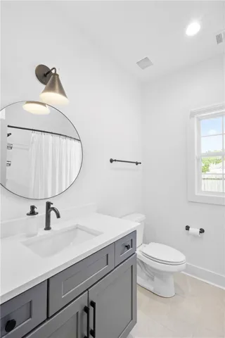 A pristine bathroom featuring a sleek vanity and modern fixtures under a wall-mounted light.