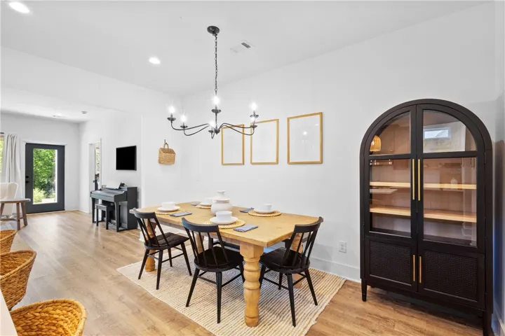 A refined dining space features wood flooring and a modern chandelier, creating an inviting atmosphere for meals.