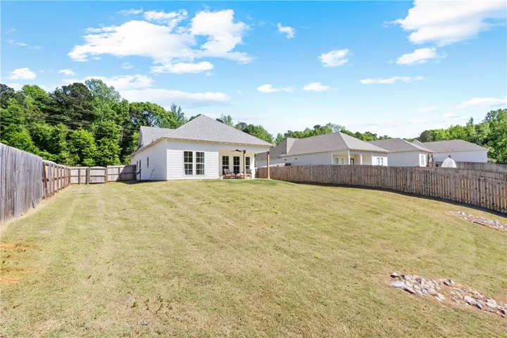 This expansive backyard offers ample green space and a covered patio for outdoor enjoyment.