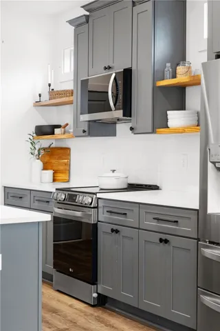 Modern kitchen with gray cabinetry, white countertops, and open shelving creates a streamlined culinary space.