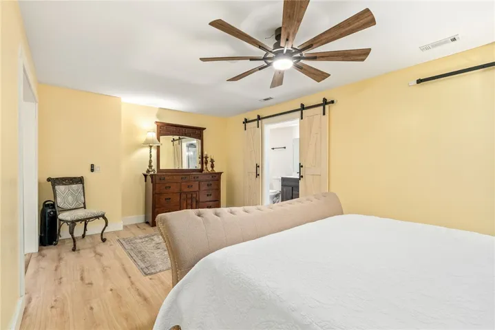 This spacious bedroom features warm tones and a functional ceiling fan, offering a comfortable retreat.