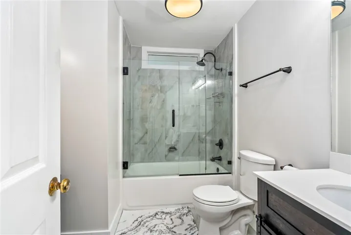 This sleek bathroom features a modern shower-tub combination and a practical vanity.