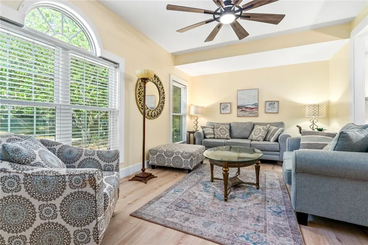 Bright and airy living area with tall windows and a ceiling fan creates a welcoming atmosphere.