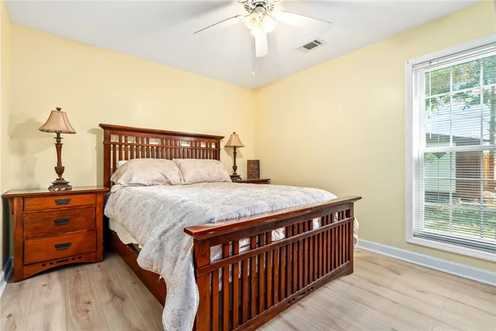 This cozy bedroom features light-toned flooring and a bright window, creating a serene and inviting atmosphere.