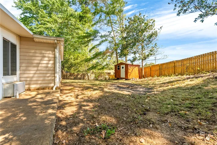 This spacious yard features a practical shed and sturdy wood fencing, perfect for outdoor living.