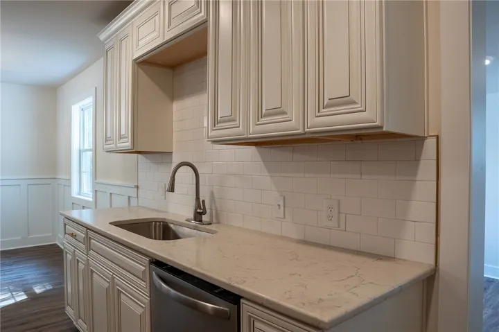 This modern kitchen features crisp white cabinetry, a subway tile backsplash, and sleek stainless steel appliances.