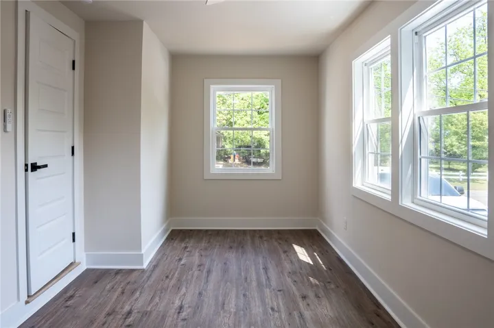 This bright room features beautiful flooring, large windows, and a classic door.
