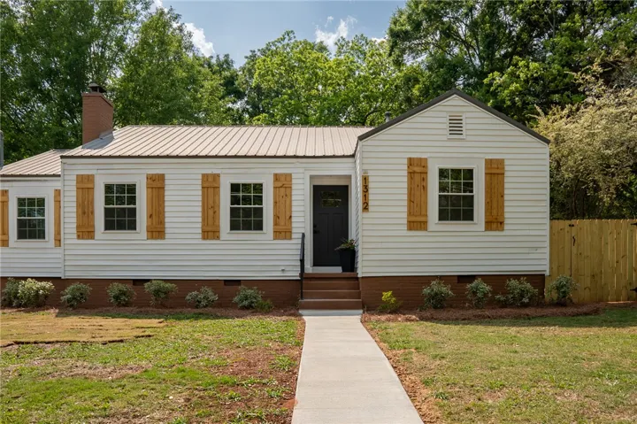 This charming residence features classic board and batten siding, a durable metal roof, and a welcoming pathway.