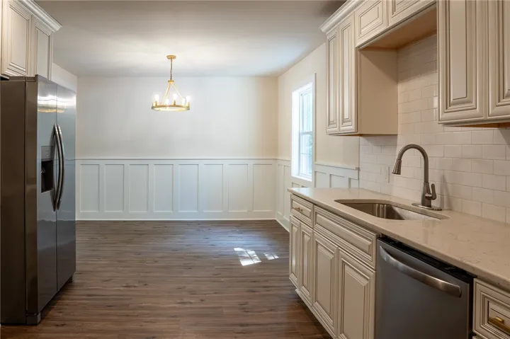 This spacious kitchen and dining area features elegant wainscoting and hardwood flooring.